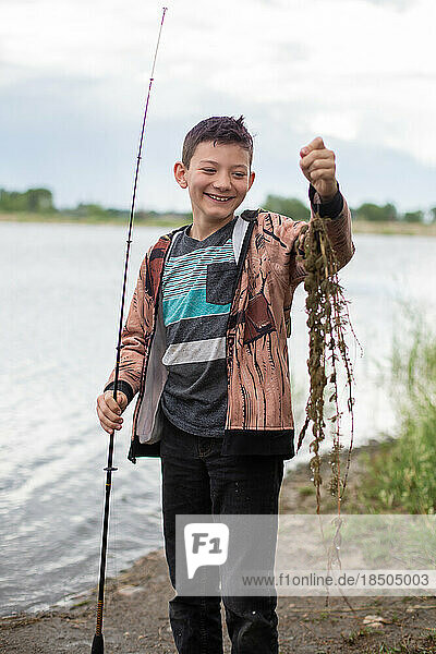 Boy laughing at seaweed caught while fishing