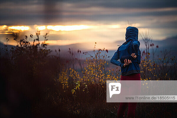 Woman zipping up hydration trail running vest at sunset