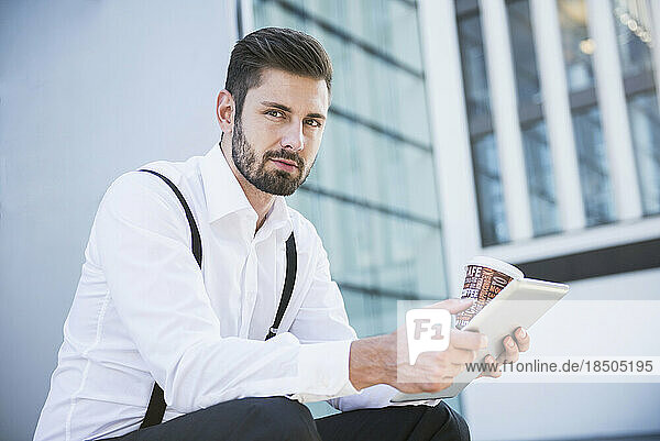 Businessman working on digital tablet with coffee  Munich  Bavaria  Germany