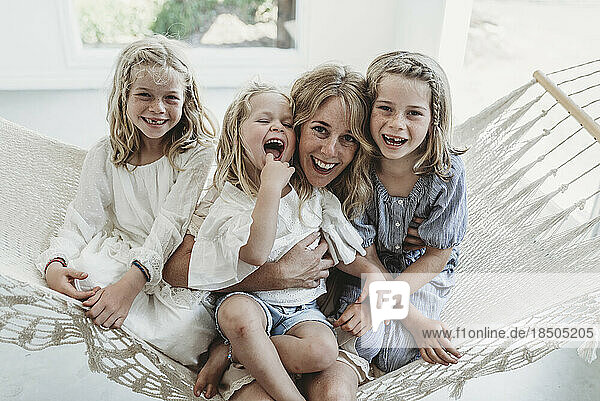 Mother and daughters cuddlin on hammock in natural light studio