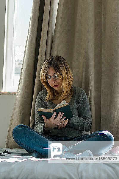 Young woman reads a book in her room