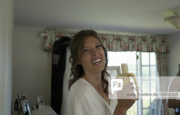 portrait of a bride on her wedding day getting ready eating a banana
