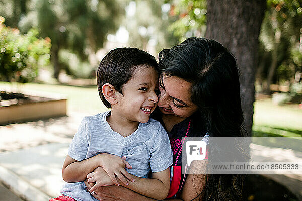 Mother & Autistic Son Smiling & Hugging Under Tree