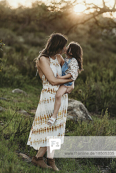 Full length view of mother and daughter kissing in sunny field
