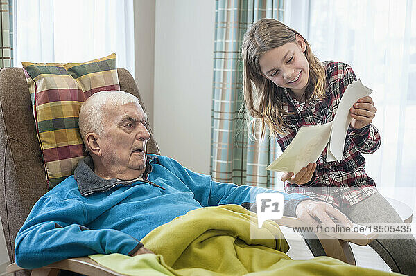Granddaughter showing old photos to grandfather in rest home