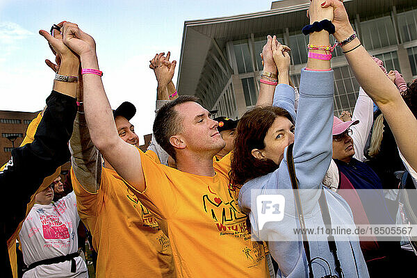 Paul Boulanger raises his hands with others at the start of the Avon Walk for Breast Cancer in Boston.