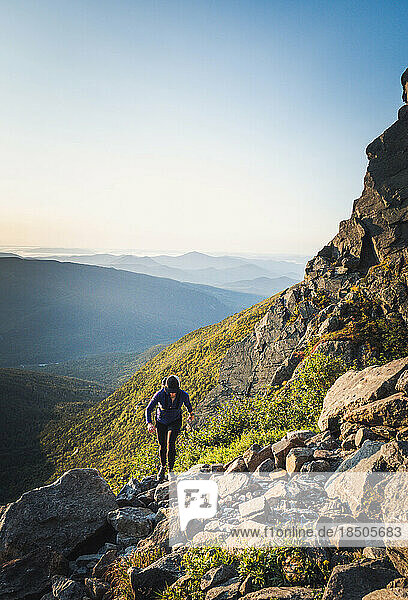 Woman hiking on rocks on mountain at sunrise