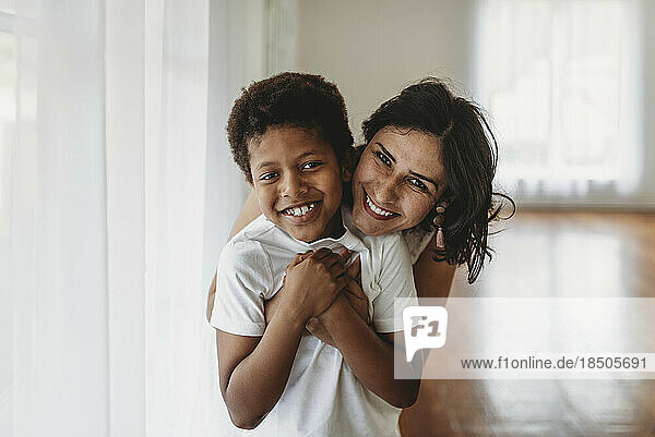 Mother and son hugging in natural light studio smiling at camera