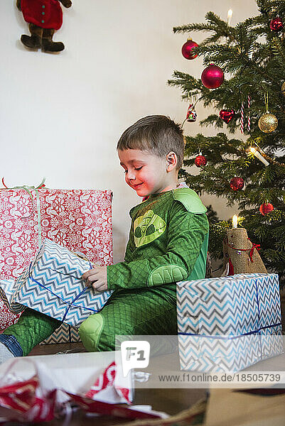 Young boy opening Christmas gift at home