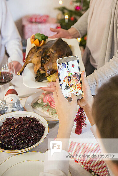 Mother with son photographing roasted duck using mobile camera