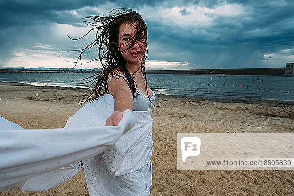 Teen girl dancing at the beach on a stormy day