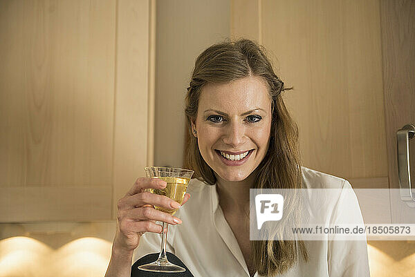 Portrait of a young woman drinking white wine and smiling  Munich  Bavaria  Germany