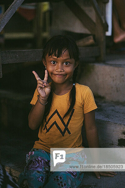 Little Balinese girl smiling shows peace.