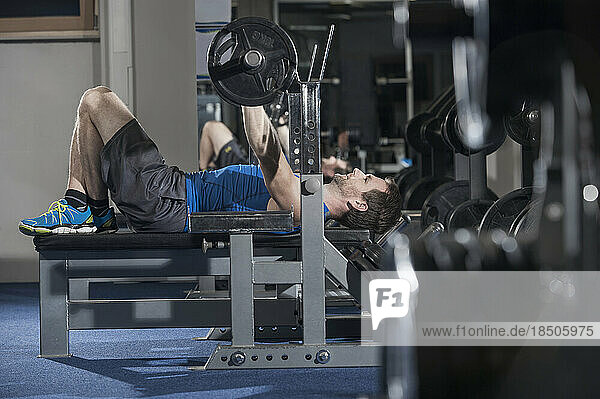 Mid adult man doing bench press in the gym  Bavaria  Germany
