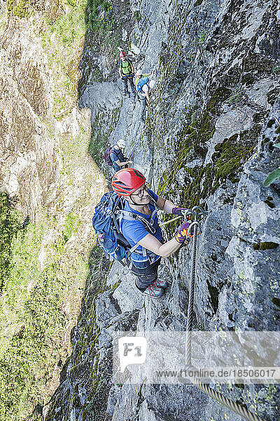 Group of people climbing rock face via ferrata towards Stuibenfall Waterfall  Otztal  Tyrol  Austria