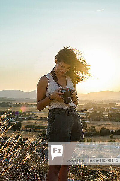 Young woman is watching her pictures in her camera on top of a mountain