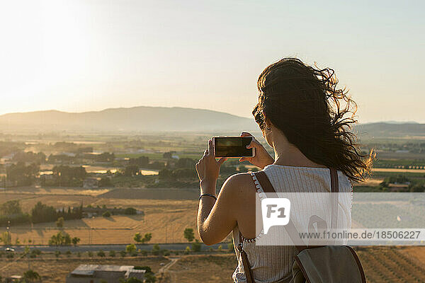 Young woman is taking a photo with her smartphone on top of a mountain