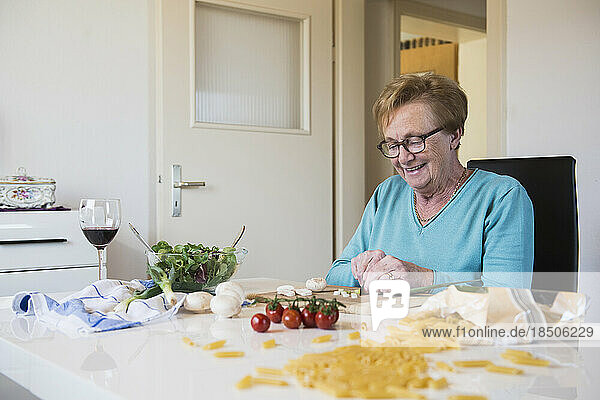 Old woman cutting spring onions at the kitchen table