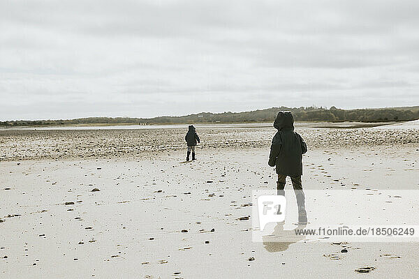 Two brothers running along empty beach