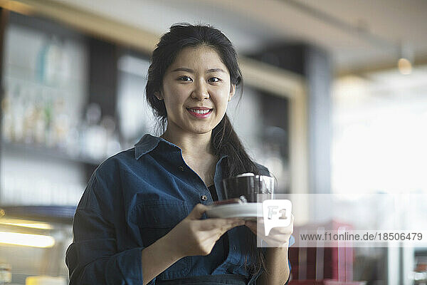 Portrait of a young waitress serving coffee in coffee shop  Freiburg Im Breisgau  Baden-württemberg  Germany
