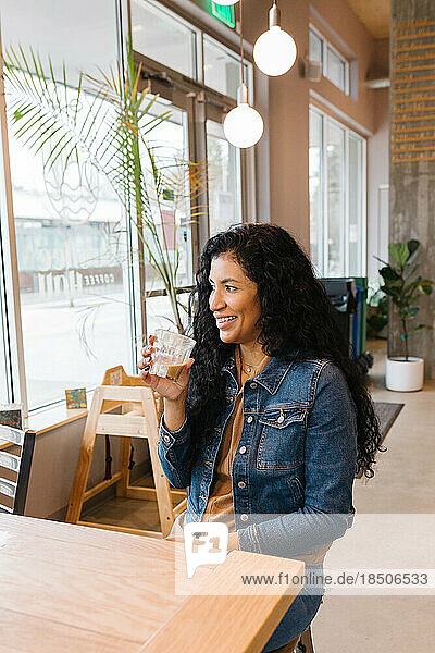 Happy Latina woman smiling holding coffee in cafe