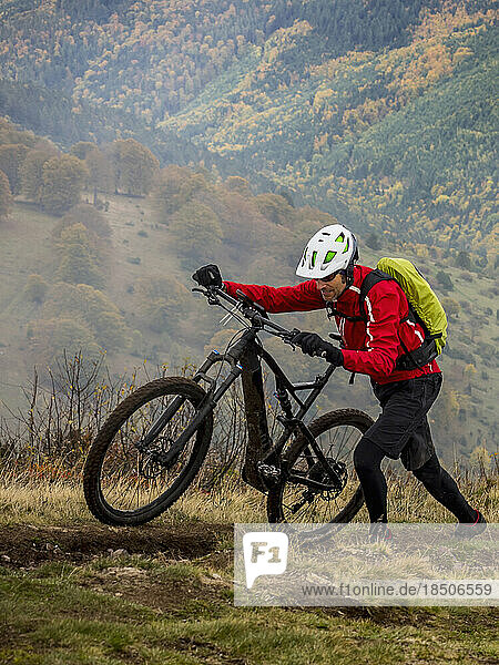 Man walking electric mountain bike on cycling tour  Vosges  France