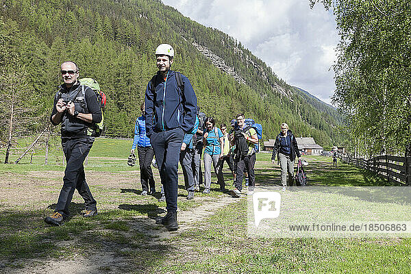 Group of climbers hiking through meadow towards Oberried climbing garden  Otztal  Tyrol  Austria