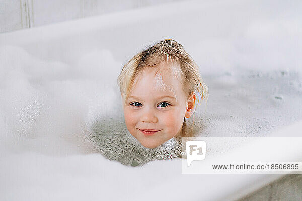 Girl baby blonde bathes at home in the bathroom