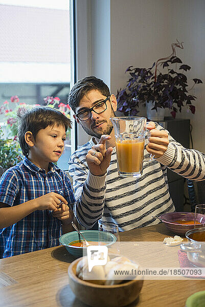 Father showing his son the measure for relation of water and juice  Munich  Germany