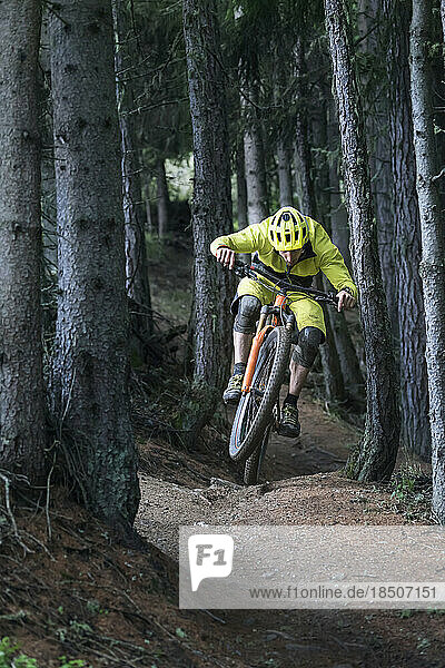 Mountain biker jumping with speed on forest path