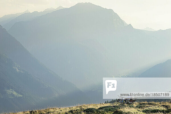Couple of mountainbikers looking at view and sitting on bench in alpine landscape  Zillertal  Tyrol  Austria