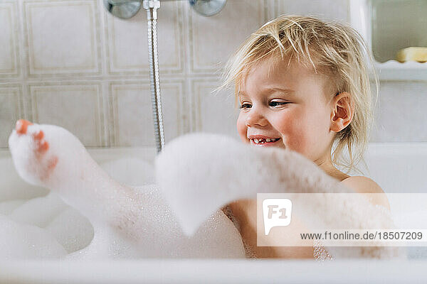 Girl baby blonde bathes at home in the bathroom