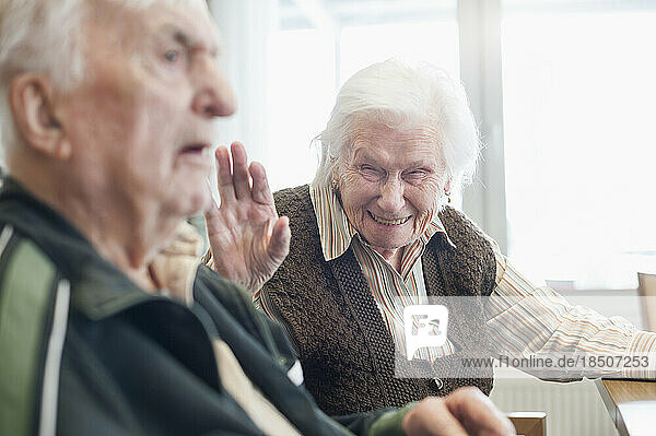 Happy senior woman with serious man at rest home
