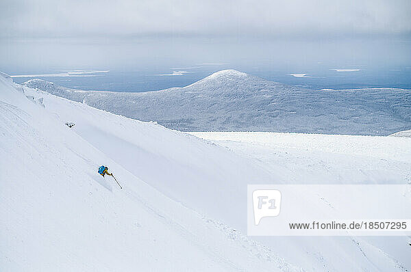 Backcountry skier skiing snow field on wide open mountain
