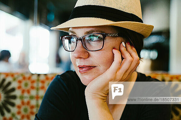 Content woman looks out window with glasses and hat
