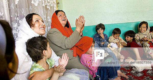 A teacher leads children in singing and clapping at a Kabul preschool.