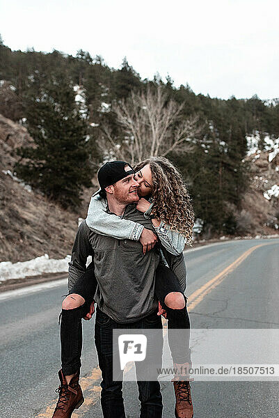 Young Man Giving Woman Piggyback Ride in Colorado Mountains in Winter