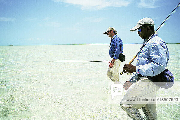Two fly-fishermen wade the saltwater flats of the Bahamas.