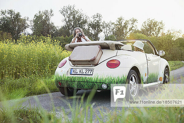 Man photographing woman in a car Beetle Cabrio  Bavaria  Germany