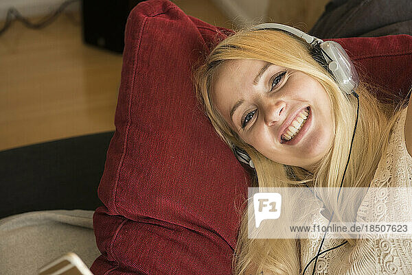 Portrait of a beautiful young woman listening to music and relaxing on sofa in the living room  Munich Bavaria  Germany