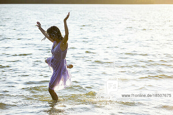 Woman in white dress dancing in water