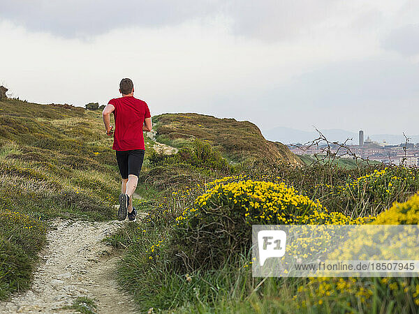 Rear view of man trail running on the cliff of Getxo