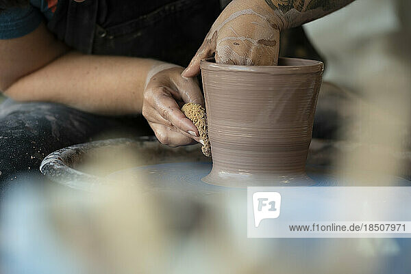 Hands crafting a pot on pottery wheel