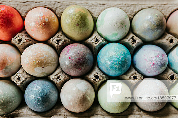 Overhead shot of close up of dyed Easter eggs in egg carton