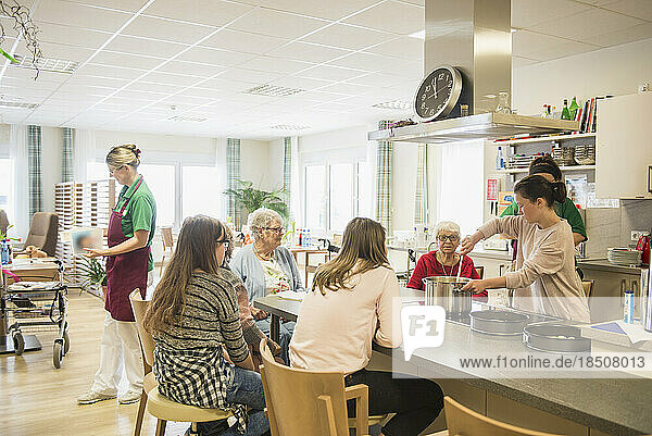 Nurse with senior women and girls preparing food at rest home
