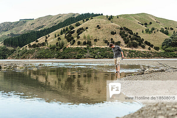 Middle age man exploring mudflat in New Zealand