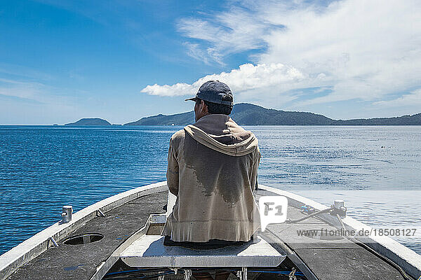 man watching the ocean from small metal dingy in Raja Ampat Indonesia