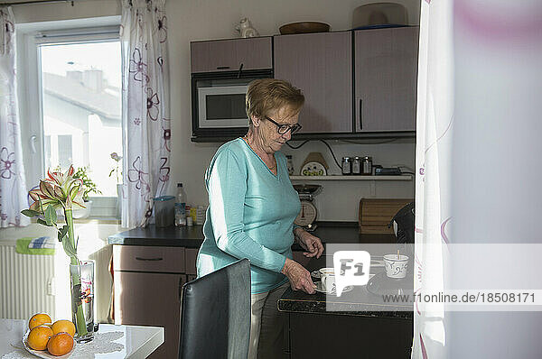 Senior woman taking cup of coffee from kitchen counter
