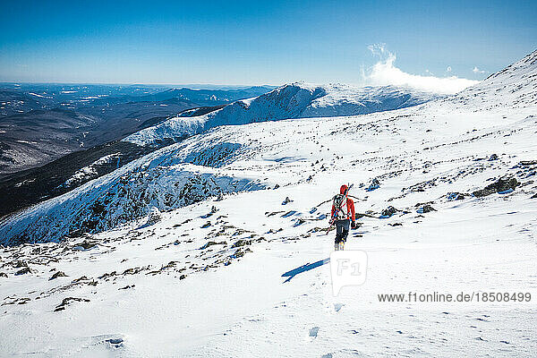 Ski mountaineer walking through frozen snow field on mountain