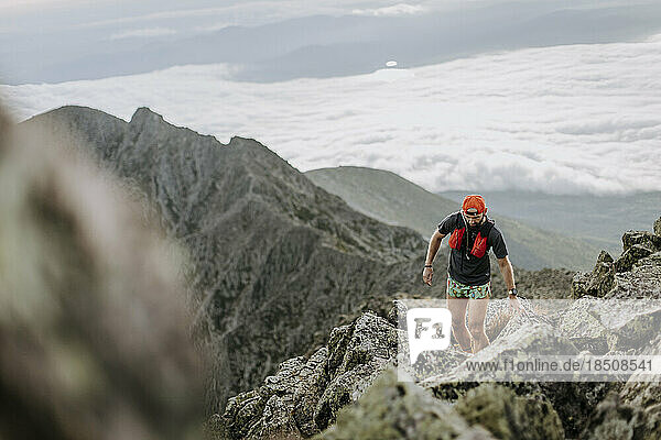 Hiker walks rocky trail above the clouds on Katahdin  Maine